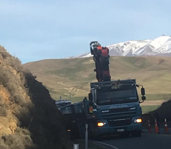 A Fulton Hogan truck is moved from the scene after rolling on State Highway 85 near Omakau this...