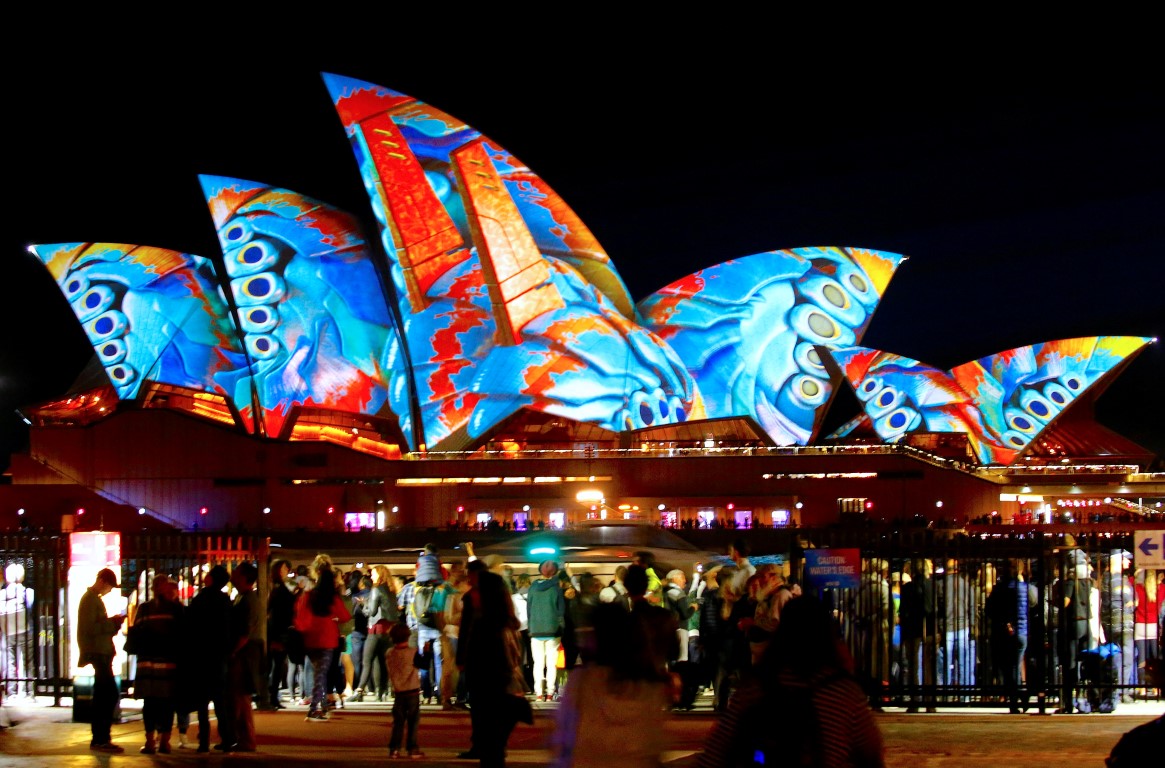 People watch as the Sydney Opera House is illuminated.