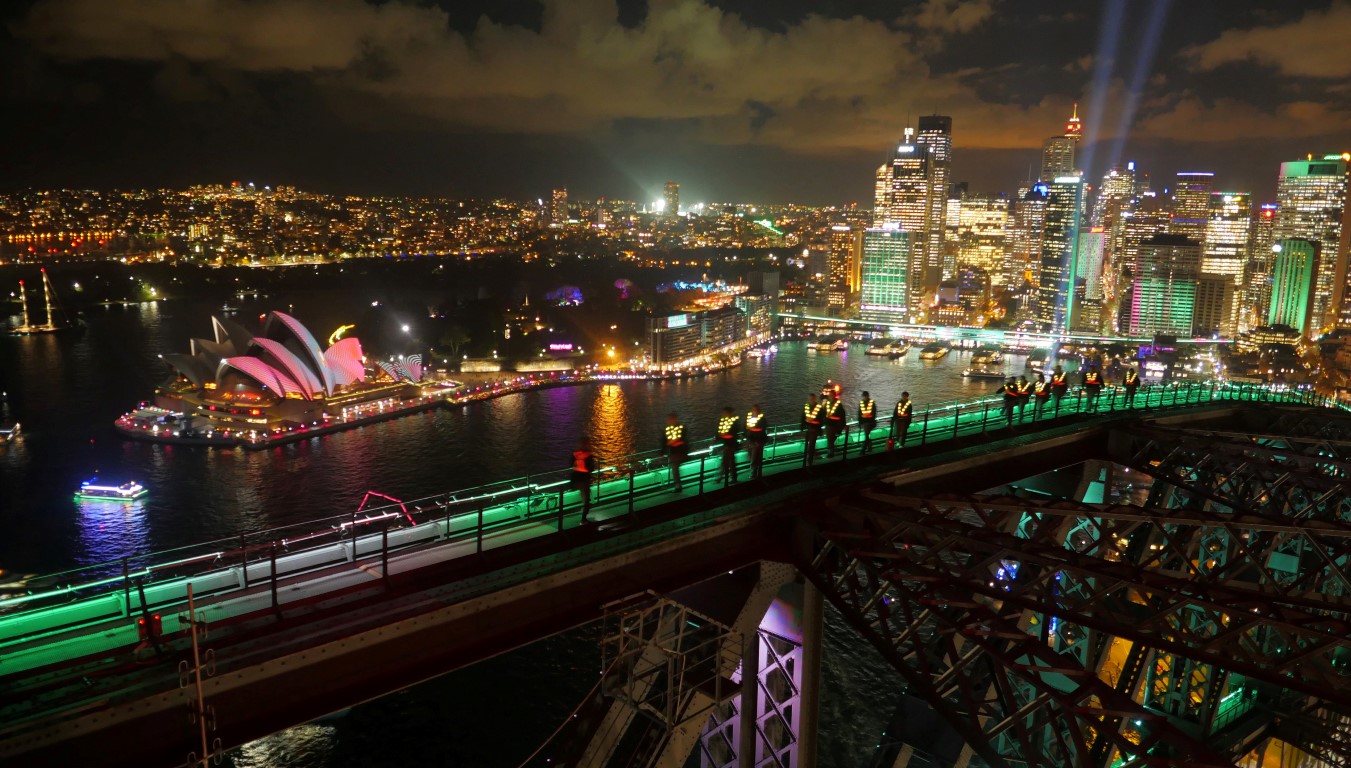 Participants in glowing vests look out to the Sydney Opera House from the Sydney Harbour Bridge...