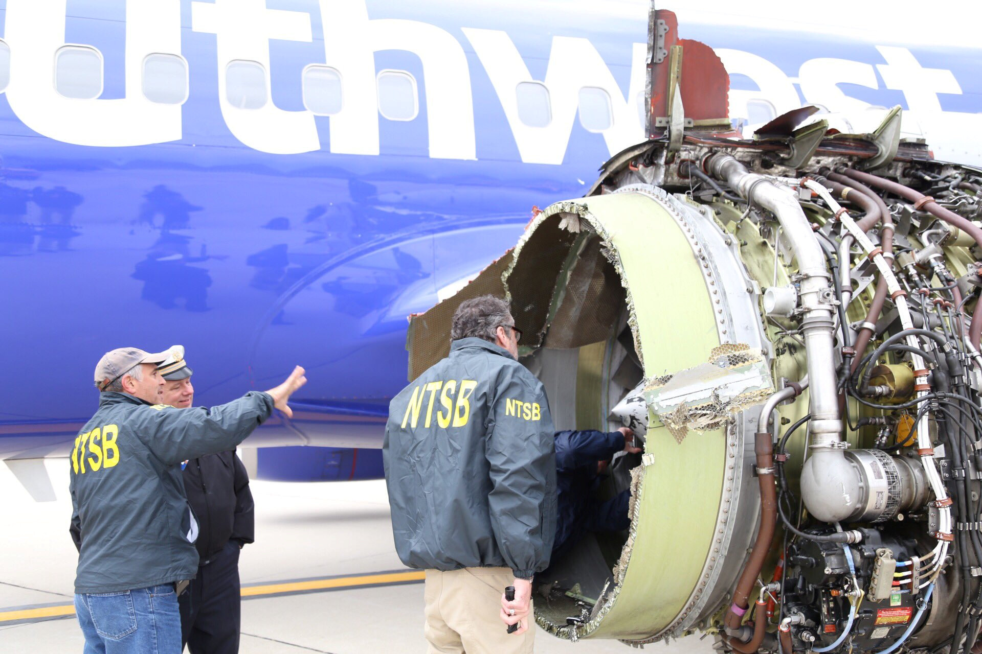NTSB investigators examine damage to the engine of the Southwest Airlines plane after it safely...