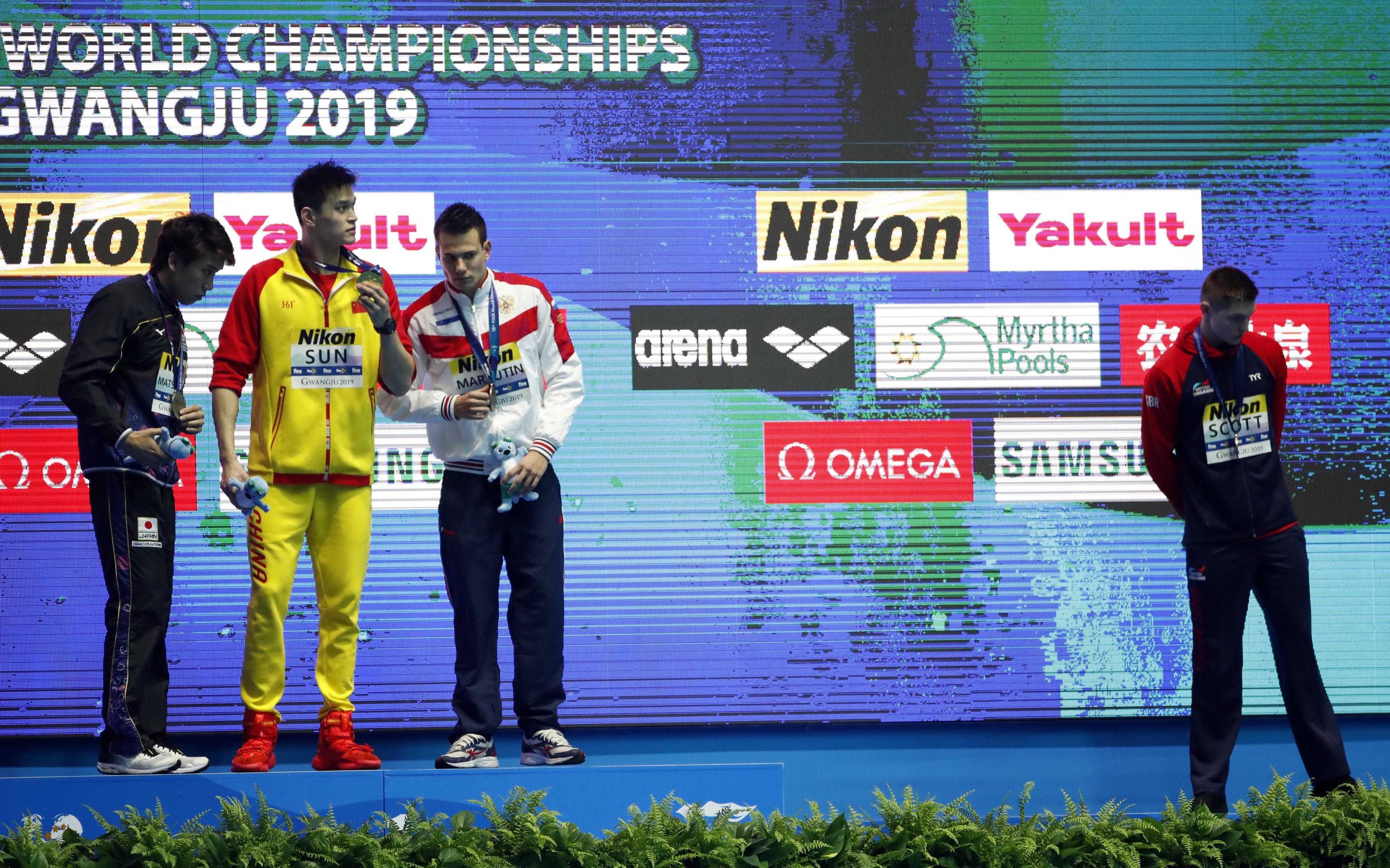 Gold medallist Sun Yang reacts on podium next to silver medallist Katsuhiro Matsumoto and joint...