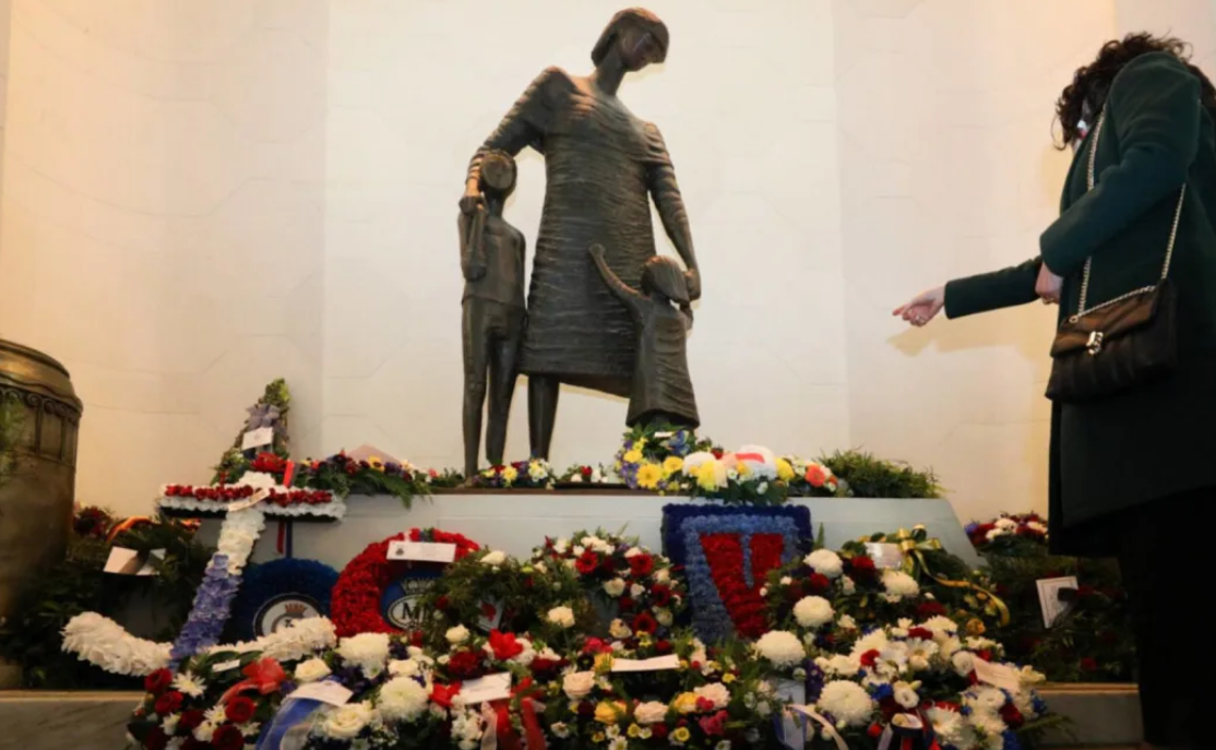 Wind buffeted the hall where wreaths were laid near a statue named 'Mother and Children',...