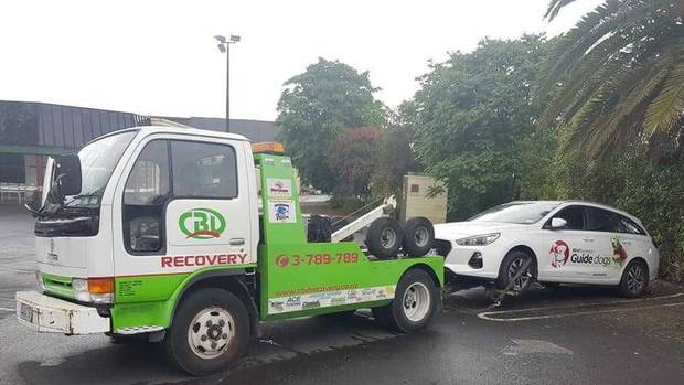 A witness said the tow truck driver demanded the charity worker pay a $100 fee to unhook the car....