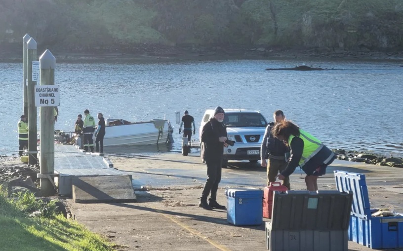 Investigators work at the scene as the capsized boat is retrieved. Photo: RNZ