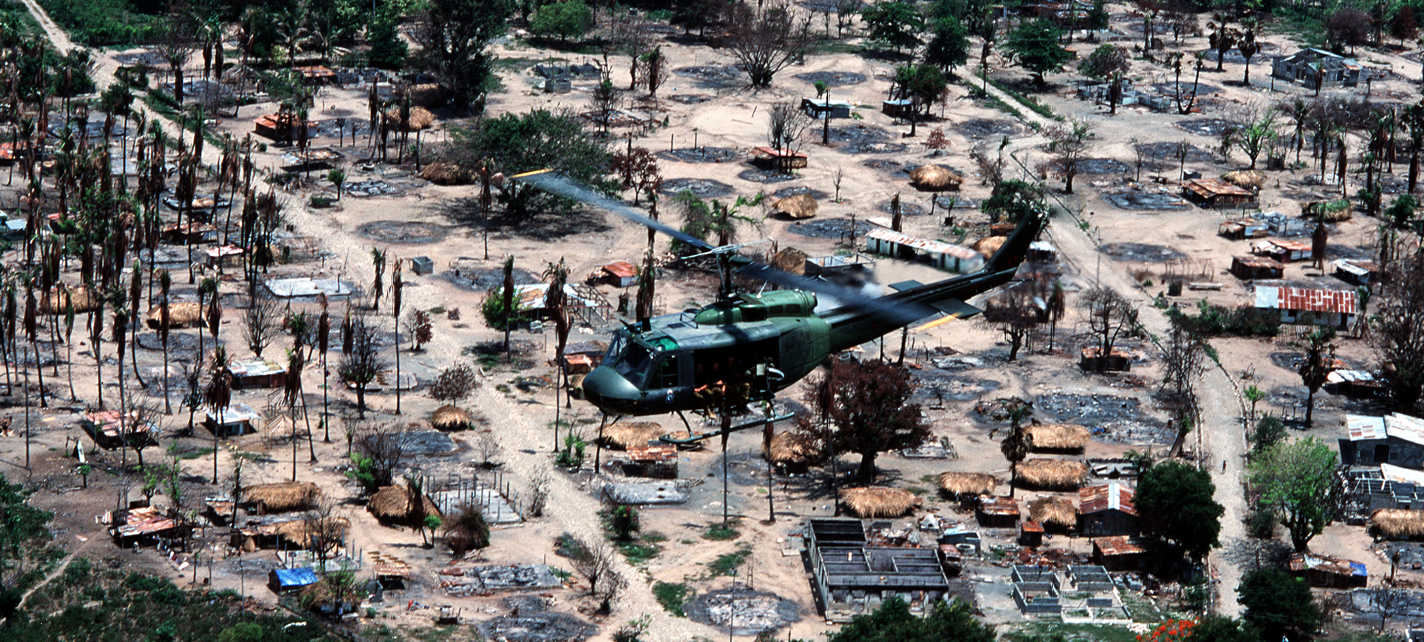 An Iroquis helicopter of No 3 Squadron, Royal New Zealand Air Force passes over a devastated East...