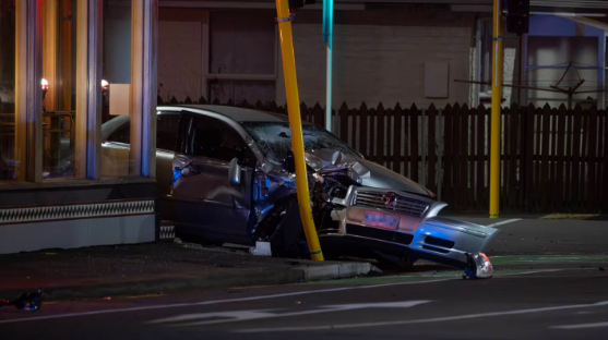 The crash scene where a motorcyclist hit a silver car which then collided with a traffic light....
