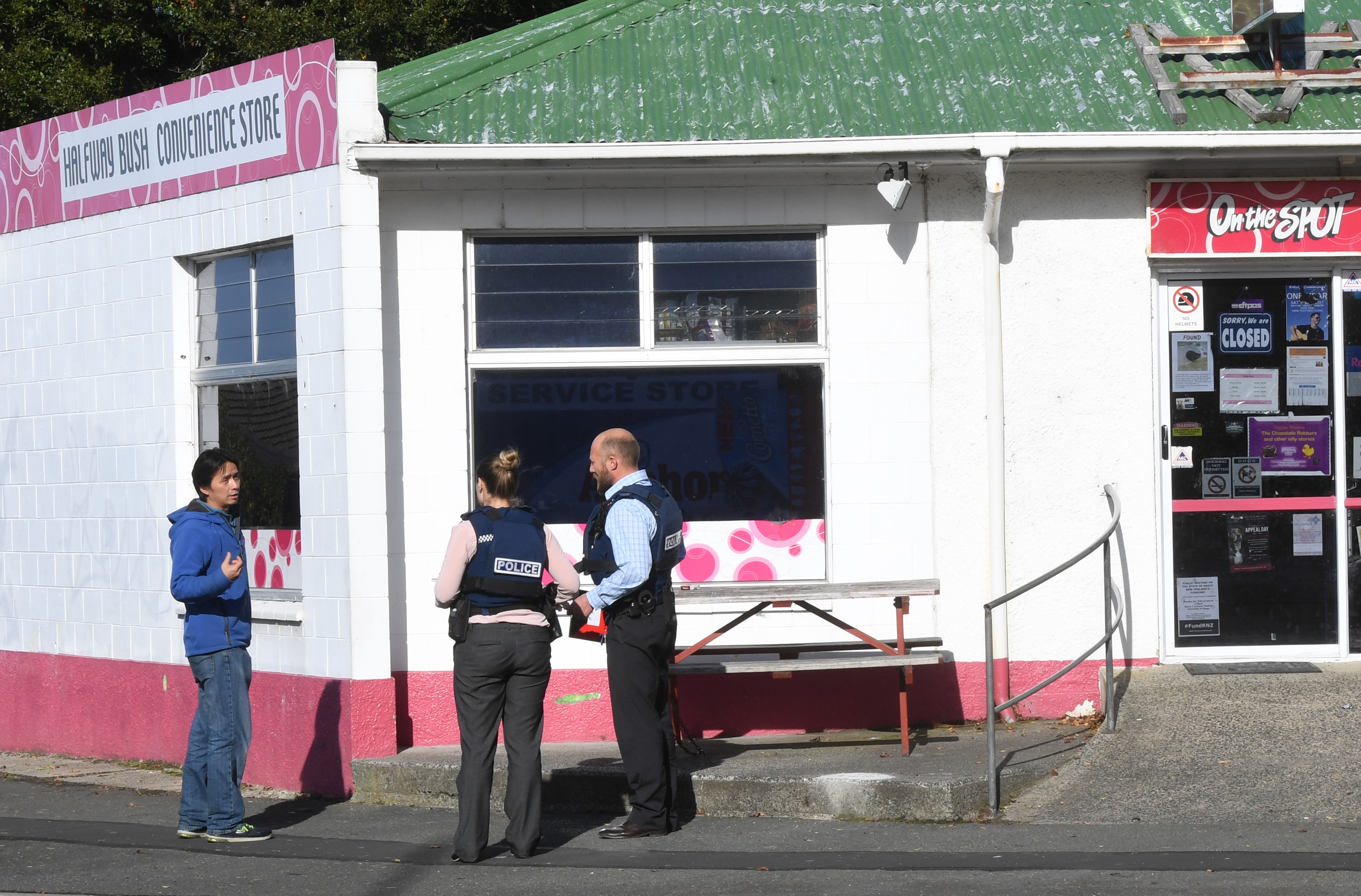 Police officers talk to the owner of the Halfway Bush store after an armed robbery in Dunedin...