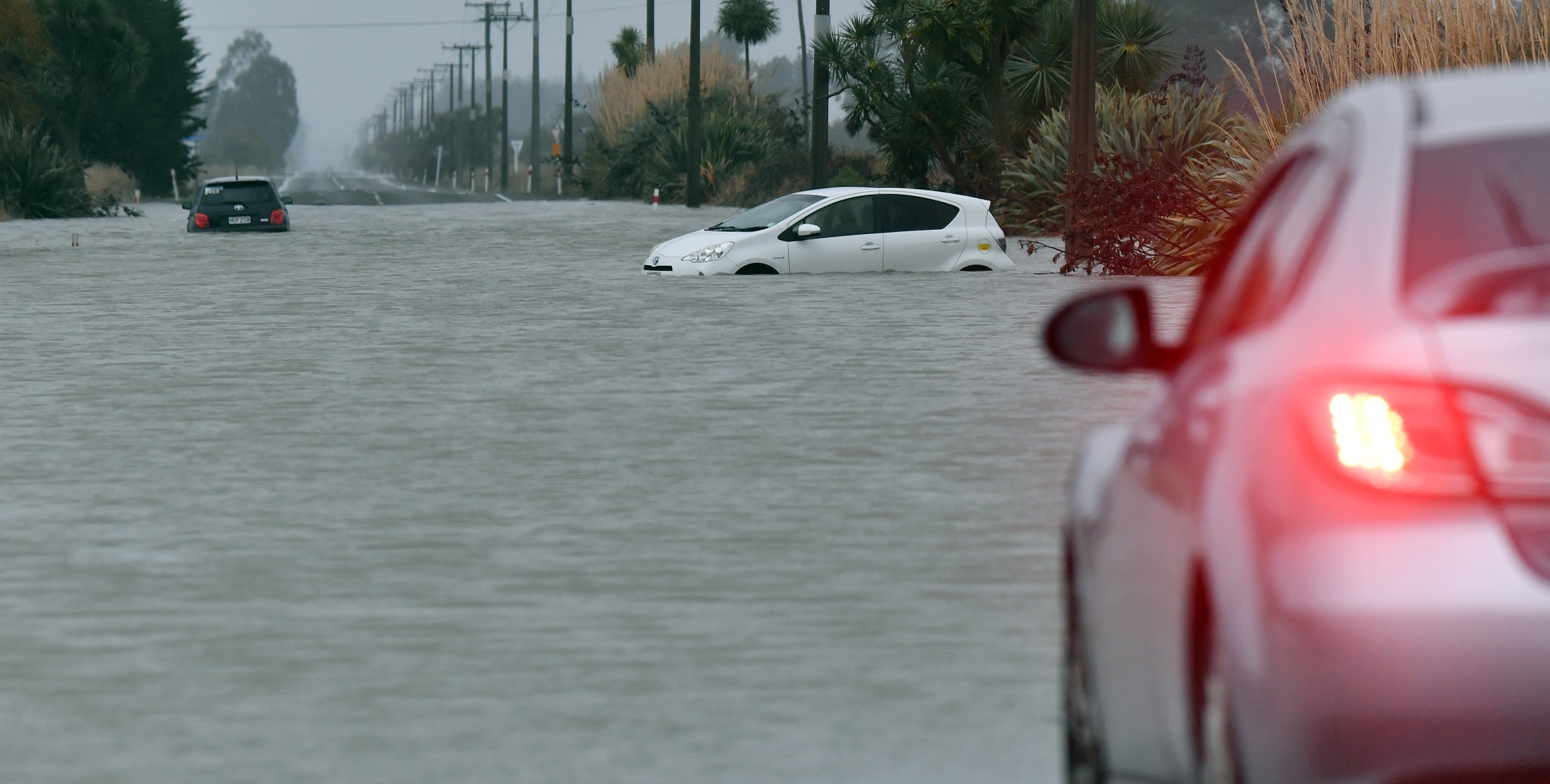 A motorist weighs up his odds over entering water flowing over SH1 north of Oamaru. Photo:...