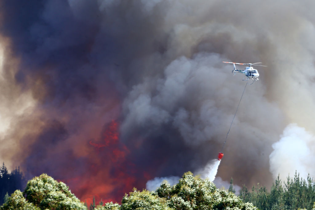 A helicopter dumps water as the fight goes on against the blaze. Photo: Getty