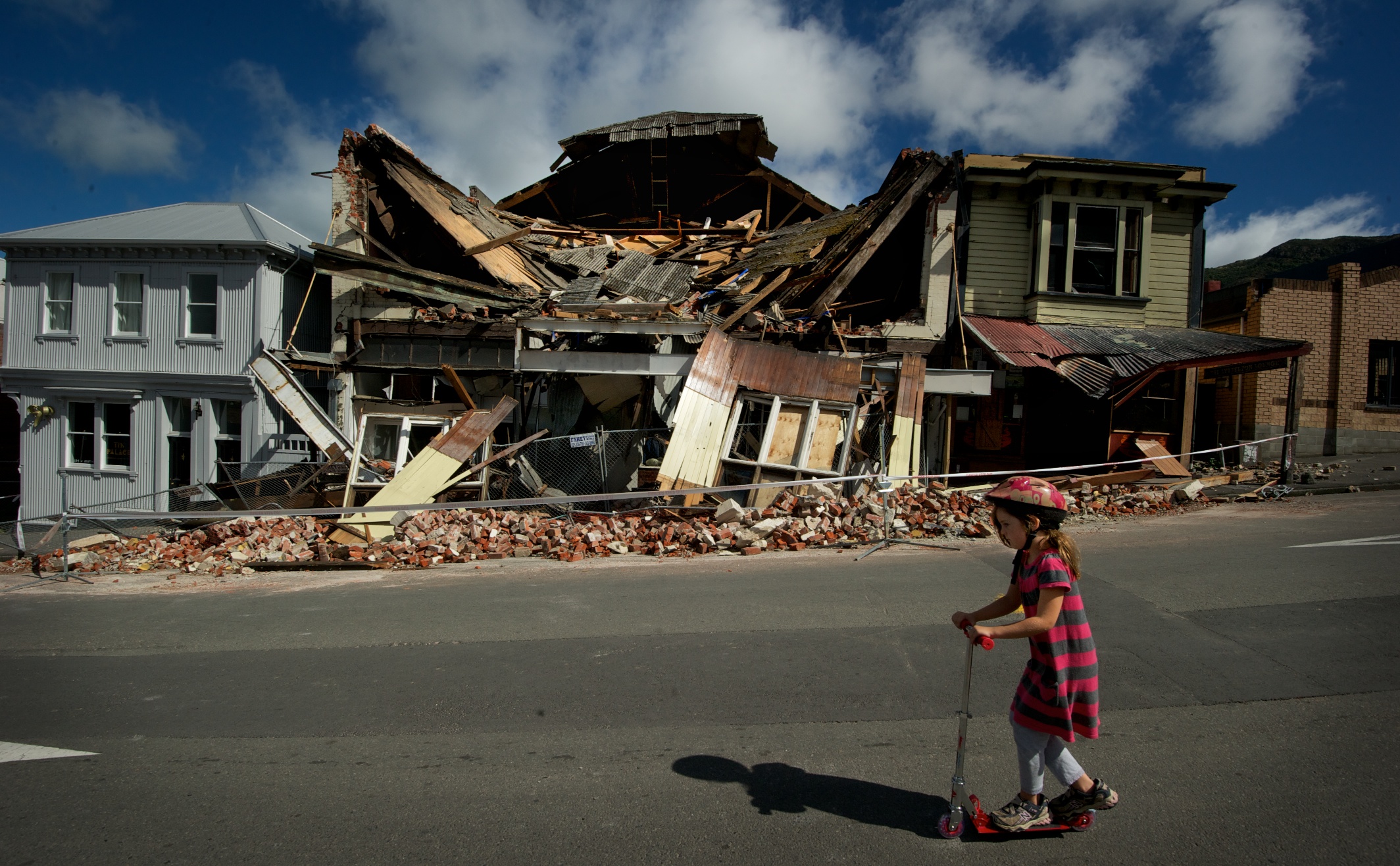 Scarlett Corbett, 7, rides past the damaged theatre in Lyttleton after the quake. Photo: Getty...