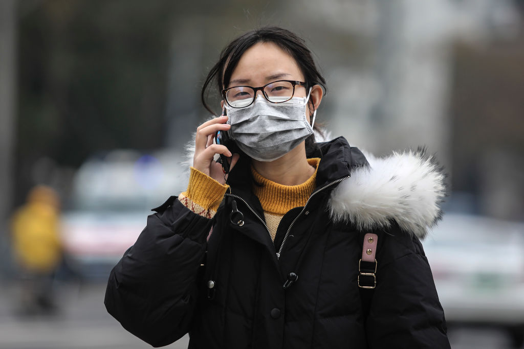 A woman wears a mask while walking past the closed Huanan Seafood Wholesale Market, which has...