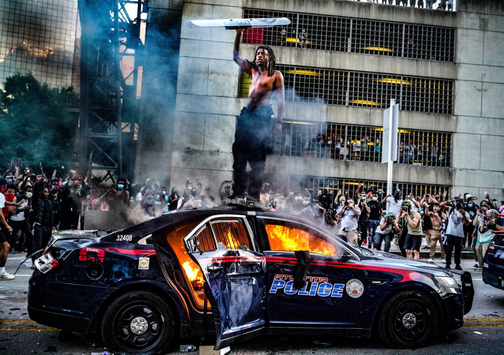 A police vehicle burns outside the CNN Center in downtown Atlanta after being set alight during a...