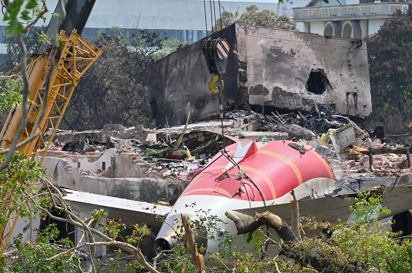 The wreckage of the crashed Air India plane is being lifted by a crane from the roof of the BJ...