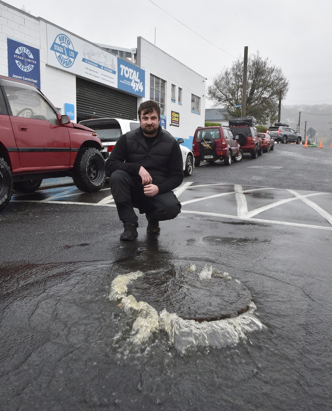Wastewater overflowing through a manhole in Surrey St outside the garage Auto Repair Otago in...