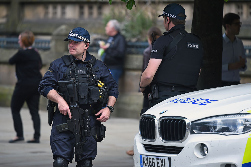 Armed police patrol Manchester's Albert Square as members of the public lay floral tributes and...