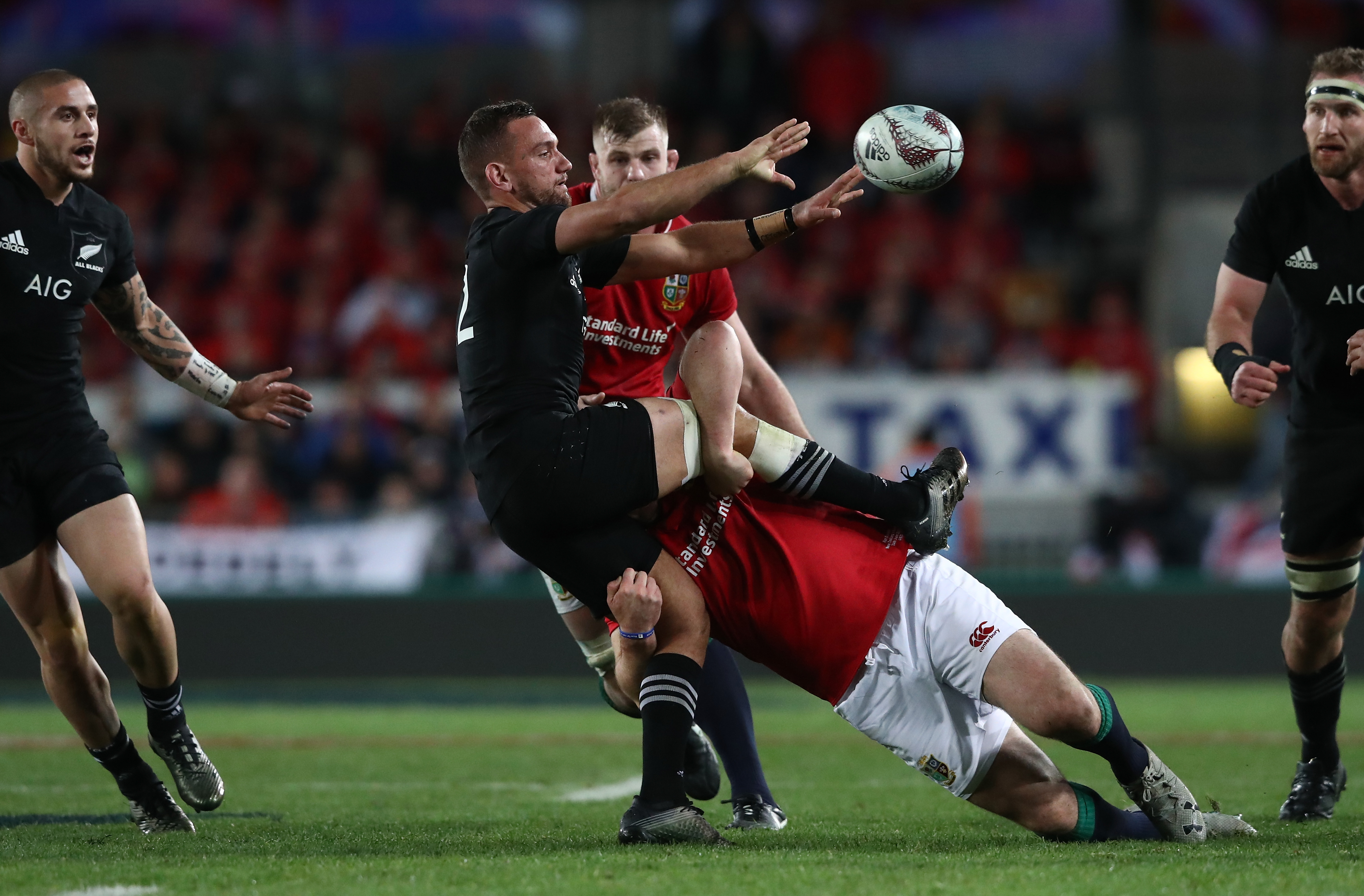 Aaron Cruden of the All Blacks offloads in the tackle. Photo: Getty