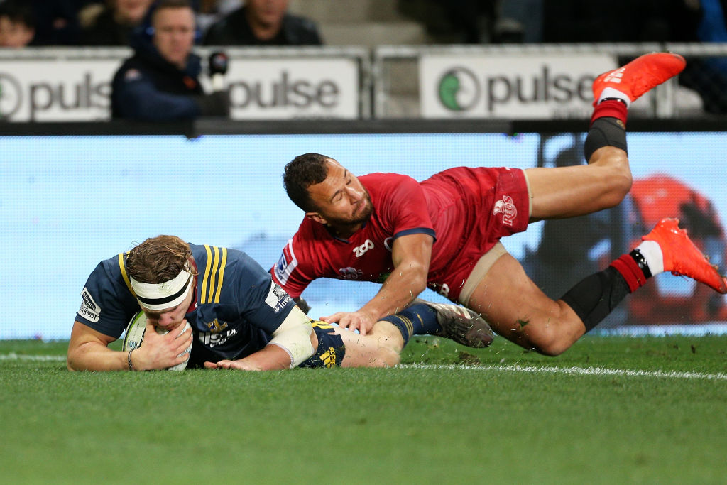 James Lentjes of the Highlanders dives over to score a try while in the tackle of Quade Cooper of...