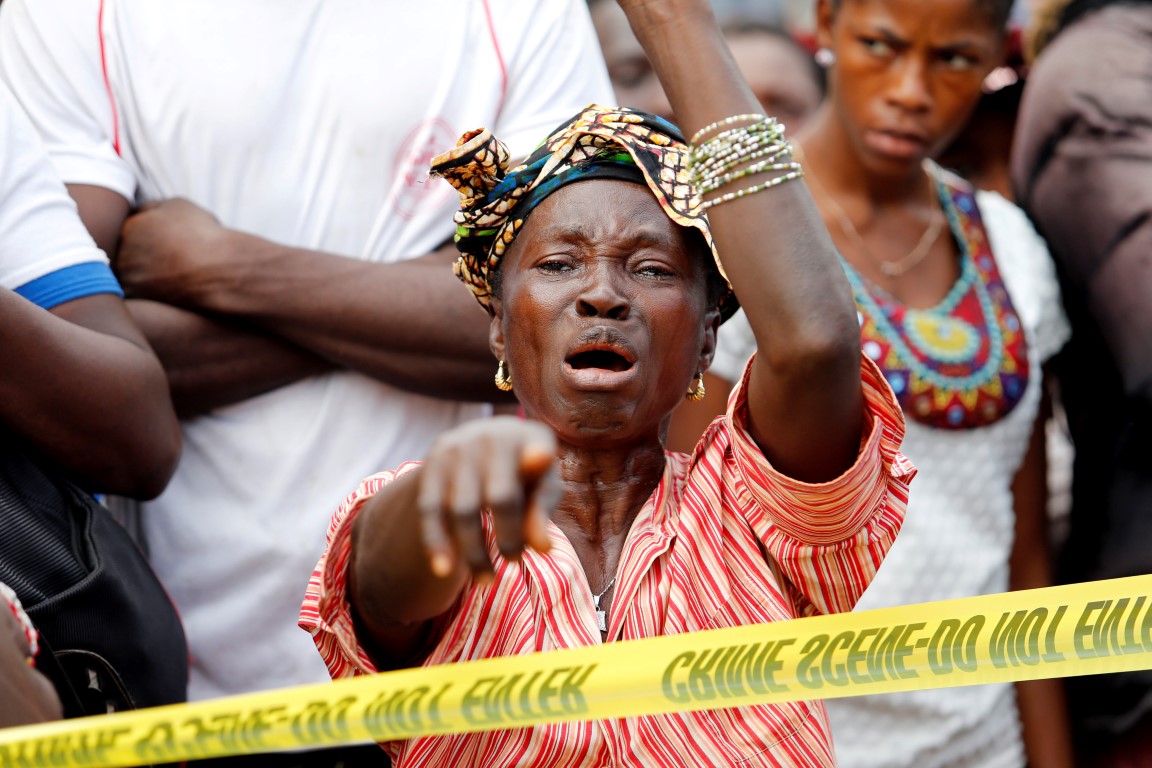 The mother of a mudslide victim grieves near the entrance of Connaught Hospital in Freetown,...