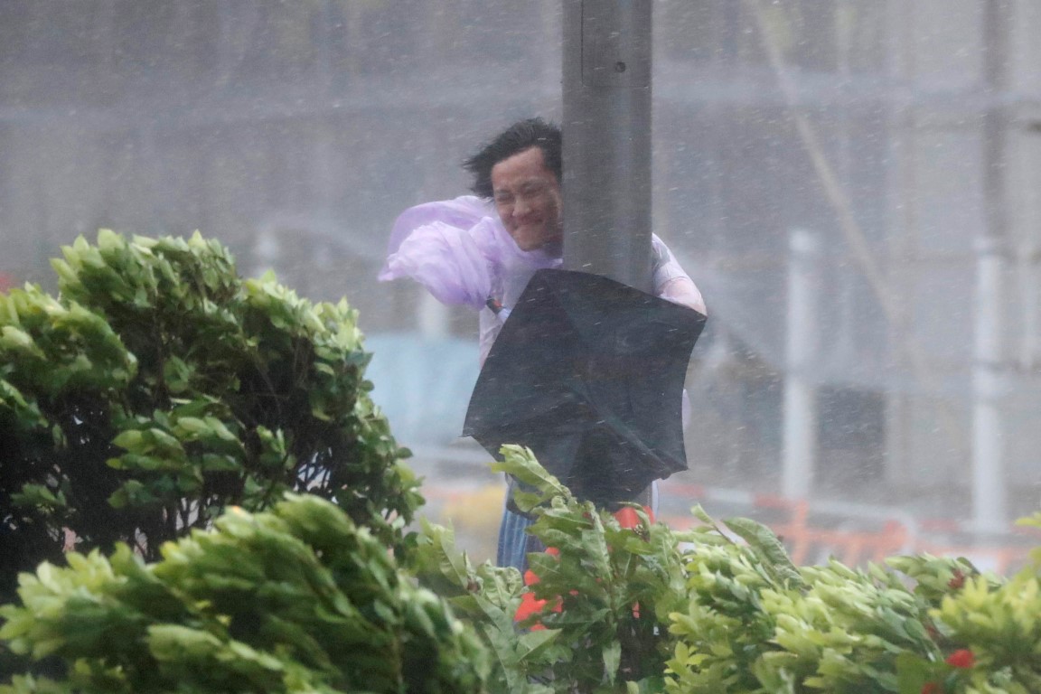 A man holds on to a lamp post as Typhoon Hato hits Hong Kong. Photo Reuters 
