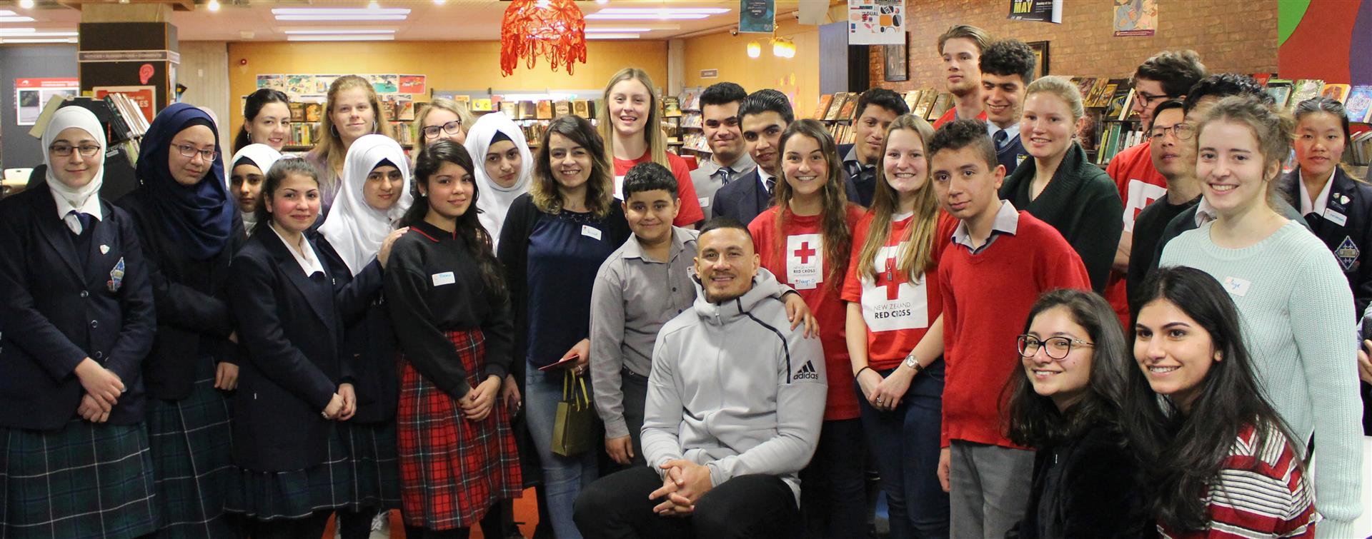 Refugee Ahmad Al Hussien (13) gets up close with All Black Sonny Bill Williams as other members of the homework club for refugee high school pupils surround him at the Dunedin Public Library. Photo: NZ Red Cross
