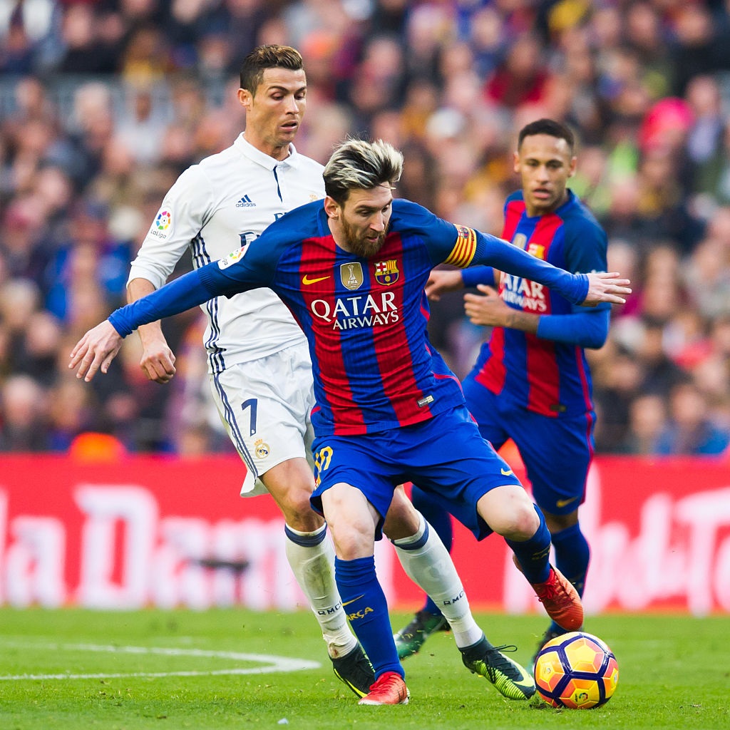 Barcelona's Lionel Messi controls the ball as Real Madrid's Cristiano Ronaldo follows him closely...