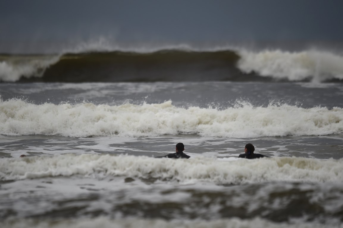 Surfers watch as waves approach in the Atlantic on the eve of storm Ophelia in an area where the...