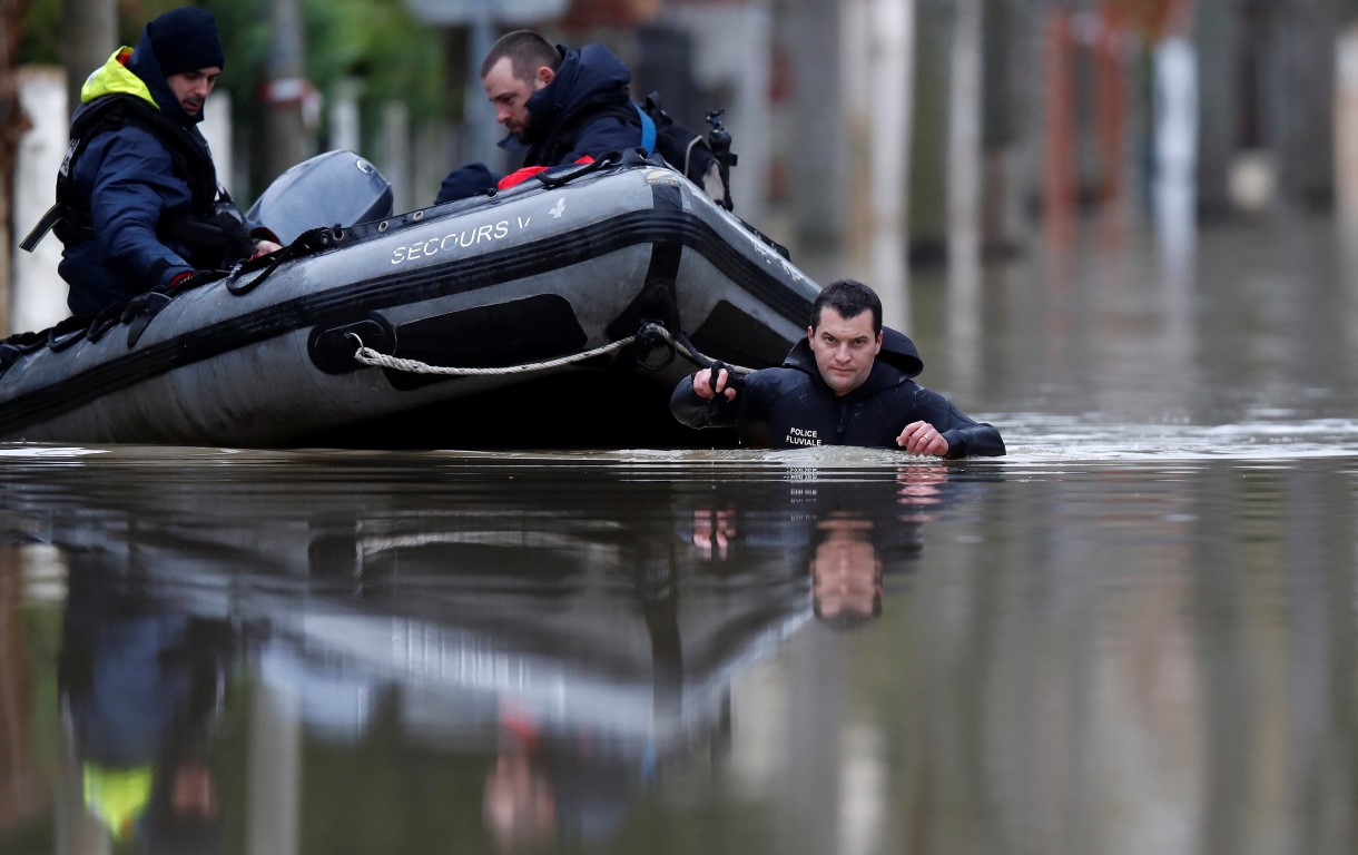 Police divers use a small boat to patrol a flooded street of a residential area in Villeneuve...