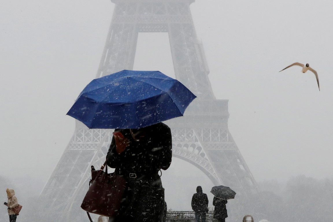 A woman uses an umbrella to protect herself from falling snow near the Eiffel Tower in Paris....