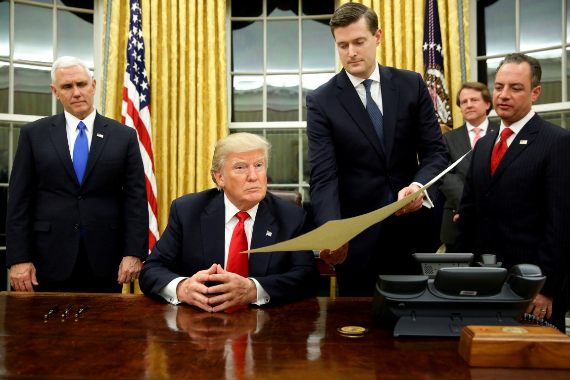 Rob Porter (then White House Staff Secretary) passes a document to President Donald Trump in the...