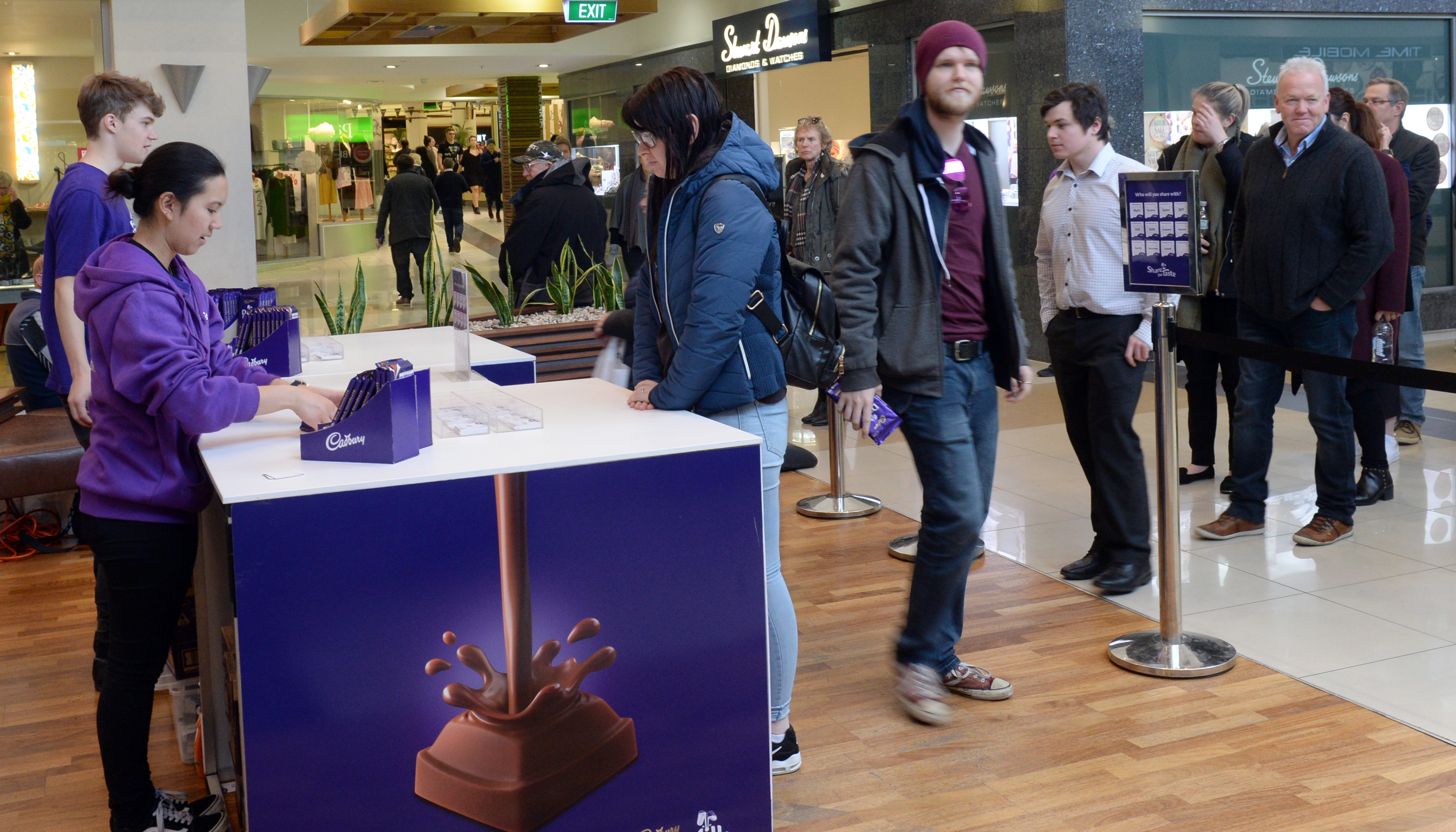 Cadbury employees Ben Epton and Yamta Zubiri hand out free chocolate to Eve Moodie and Book...