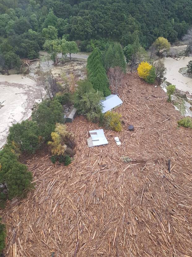 Logs and debris around a flooded house in the Tolaga Bay area. Photo:Supplied
