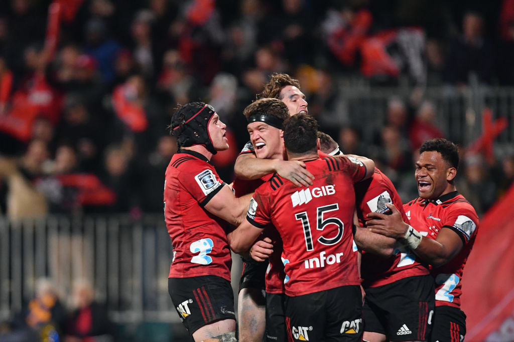 Scott Barrett (C) is congratulated by Crusaders teammates after scoring a try against the...