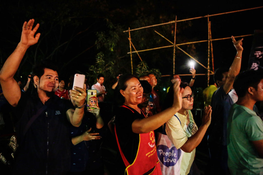 Onlookers watch and cheer as ambulances transport some of the rescued schoolboys from a helipad...