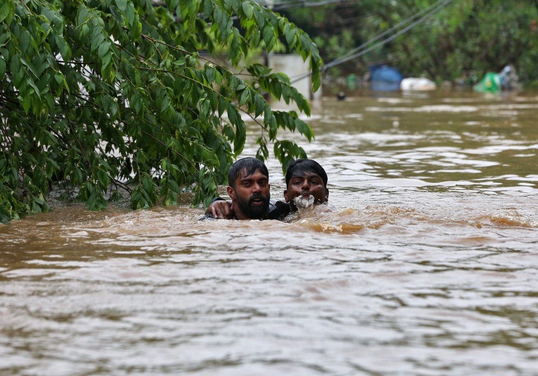 A man helps another through floodwaters on the outskirts of Kochi in the state of Kerala. Photo:...