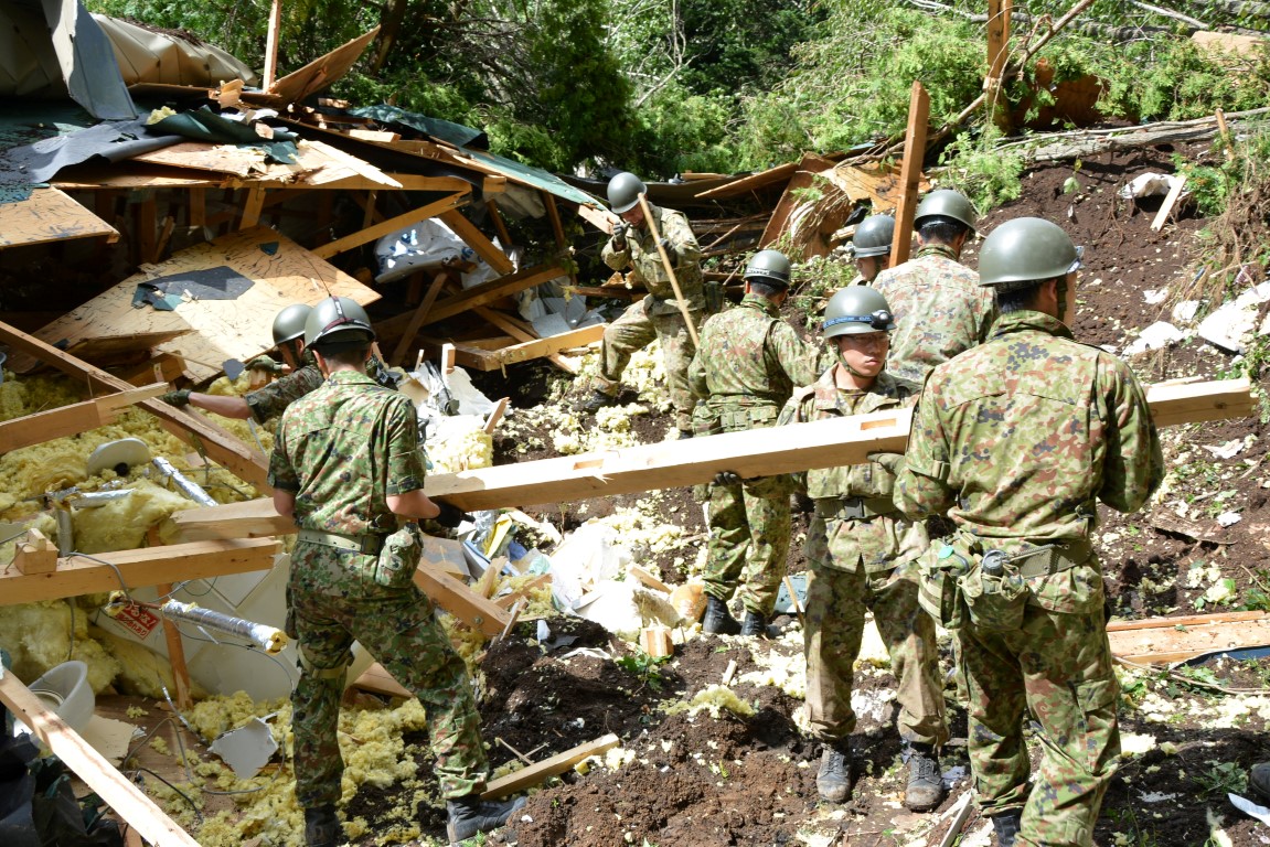 Members of the Japan Self-Defense Forces search for survivors in a house in Atsuma town that was...