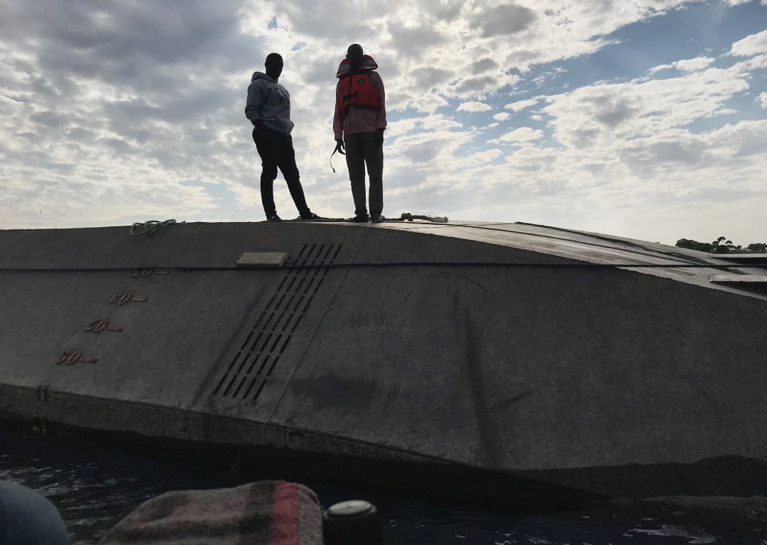 Rescuers stand on the overturned MV Nyerere as they search for bodies off the shores of Ukara...