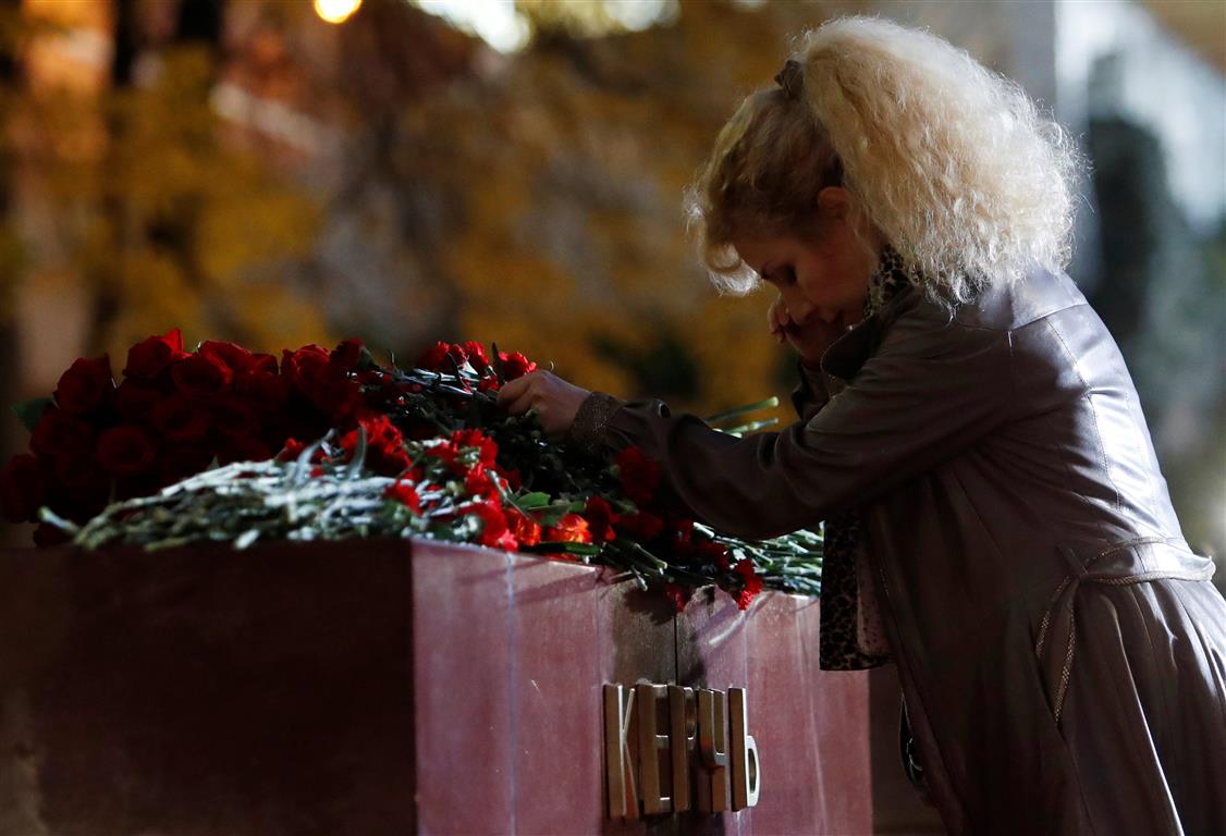 A woman lays flowers at a memorial by the Kremlin walls in Moscow to commemorate the victims of...