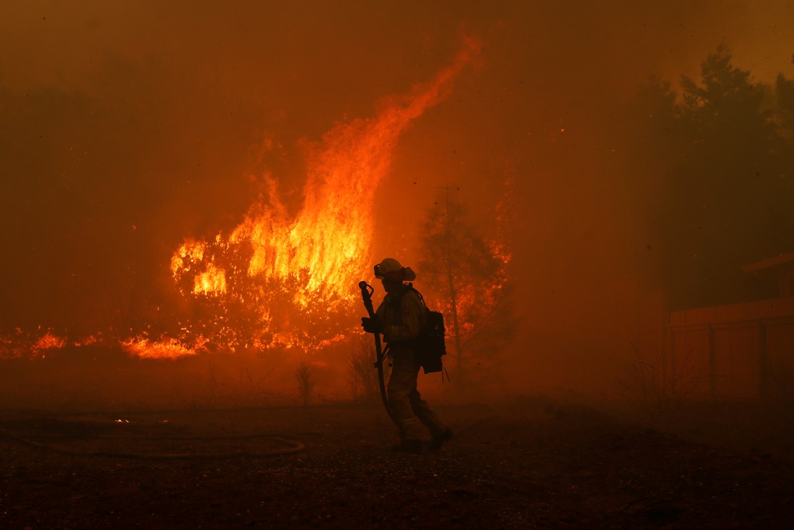 A firefighter monitors a blaze near a home while battling the Camp Fire in Paradise, California....