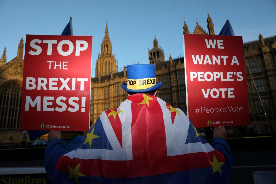 An anti-Brexit demonstrator hold placards opposite the Houses of Parliament, in London. Photo:...