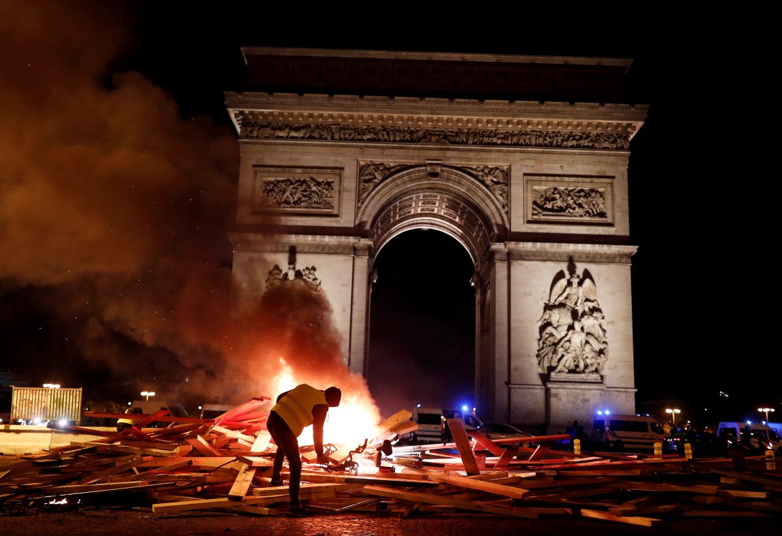 A protester beside a burning barricade during a protest against higher fuel prices, on the Champs...