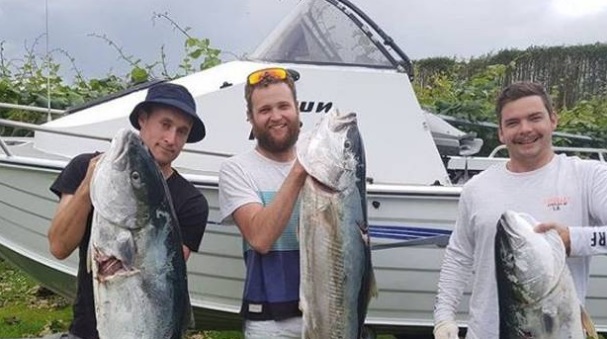 Kevin Lloyd (right) with the kingfish he managed to land despite being attacked by a shark. Photo...