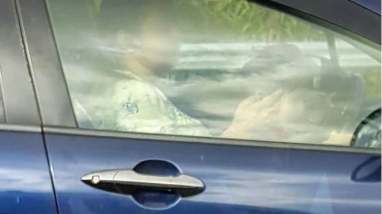 A child sitting on the lap of a woman texting while driving on the Southern Motorway. Photo:...