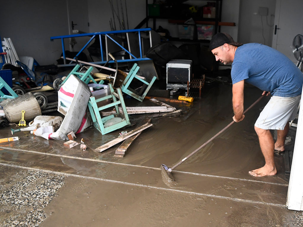 Townsville resident David Mitchell sweeps out his muddy garage after floodwaters receded in the...