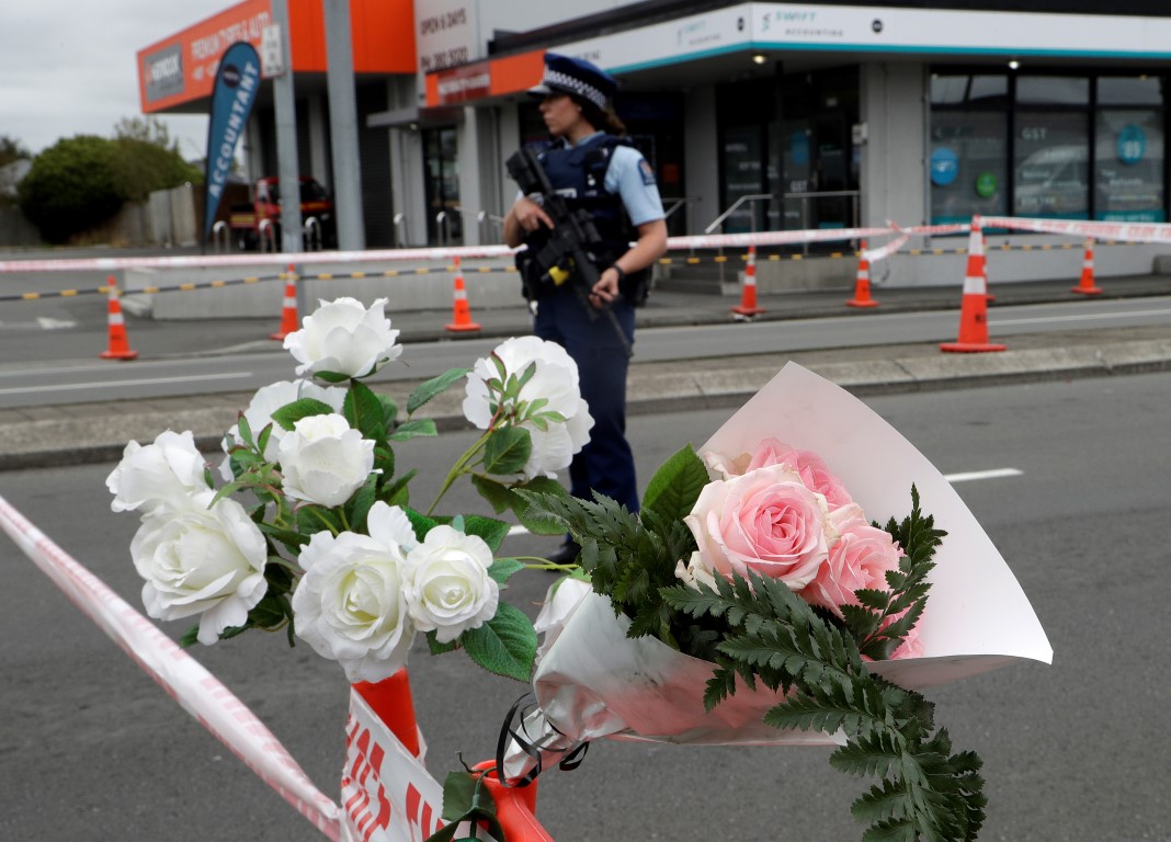 A police officer stands near a floral tribute left at a cordon at an intersection near the...