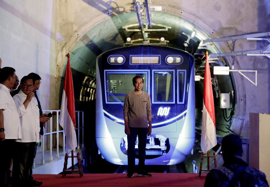 Indonesian President Joko Widodo (C) in front of a Jakarta Mass Rapid Transit train during the...