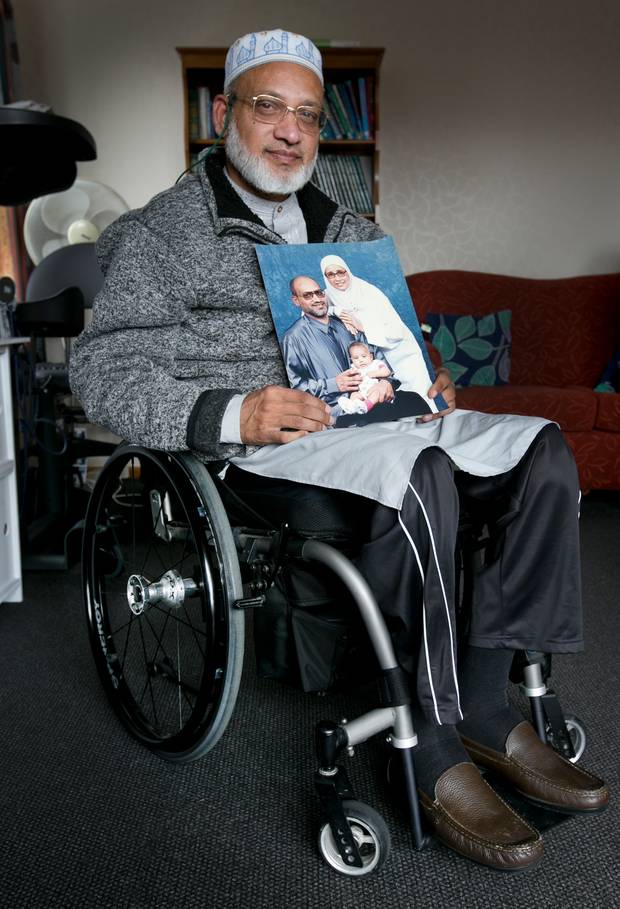 Farid Ahmed pictured holding a photograph of his family, including wife Husna Ahmed who was...