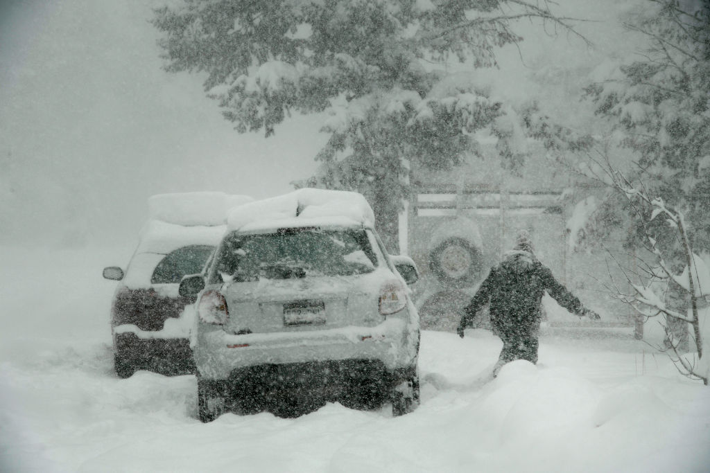 A woman tries to brush snow from her car in Nederland, Colorado. Photo: Getty