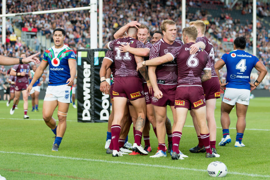 Manly players celebrate a try as the Warriors' Roger Tuivasa-Sheck (L) reacts during their NRL...