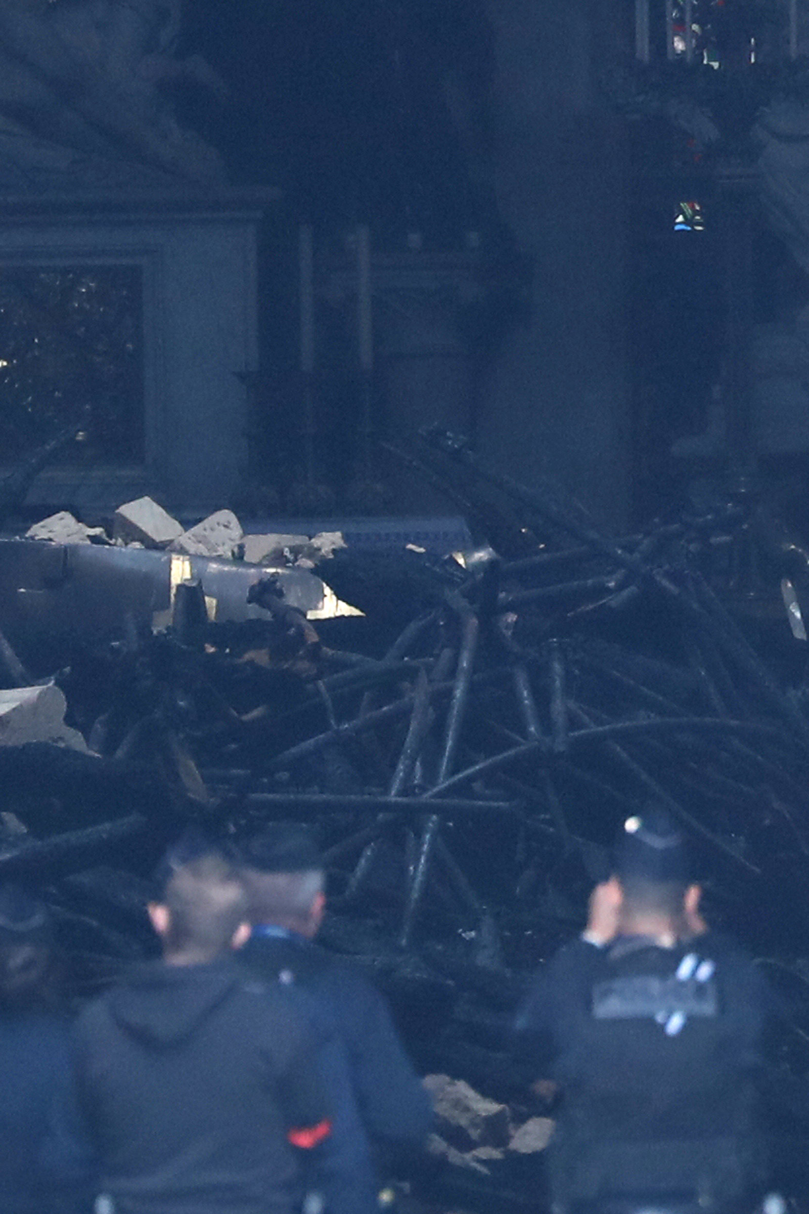 French police look at debris inside Notre-Dame Cathedral after a massive fire devastated large...
