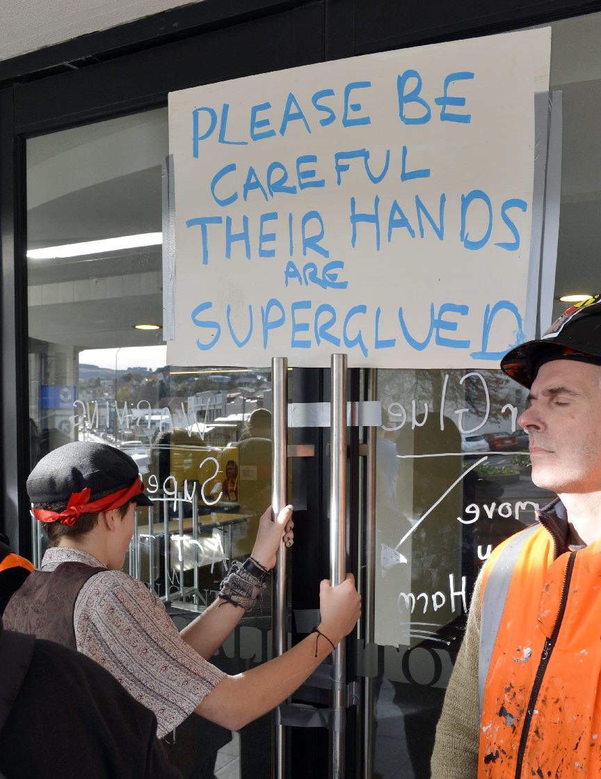 A protester with hands superglued to the front doors of the Dunedin Town Hall. Photo: Gerard O'Brien